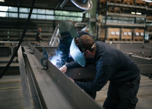 Zwei Personen schweißen Stahl in unserer Fabrikhalle.