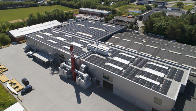 Luftaufnahme der Haarup Maskinfabrik mit Solarzellen auf dem Dach und den umliegenden Feldern.