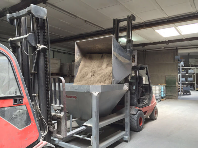 Austauschbares Silo, das von einem Bagger mit Sand gefüllt wird.